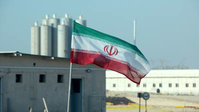Irans flagga vajar framför iranskt kärnkraftverk.