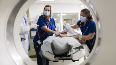 Sairaanhoitaja Sonja Savolainen valmistelee potilasta aivojen tietokonekuvaan.