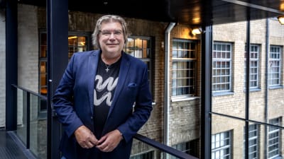 Man, Mikael Lindfelt vid Åbo Akademi, står framför kameran i mörkblå satinkostym.