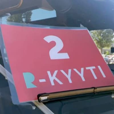Punainen kyltti, jossa numero kaksi ja teksti R-kyyti pikkubussin etuikkunalla.