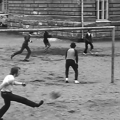 Folk som spelar fotboll på en sandplan.