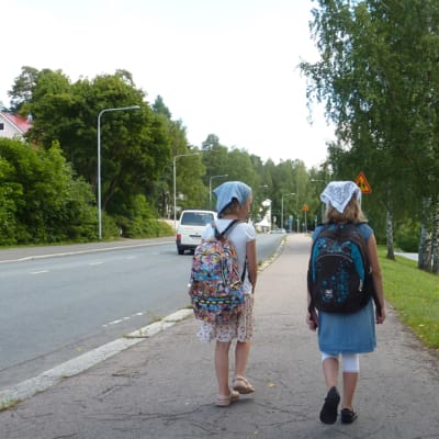 Kaksi reppuselkäistä tyttöä koulutiellä