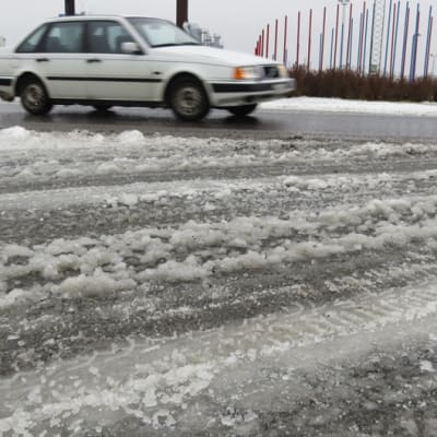 Talvinen luminen tie Kemissä, valkoinen Volvo ajaa kiertoliittymässä.