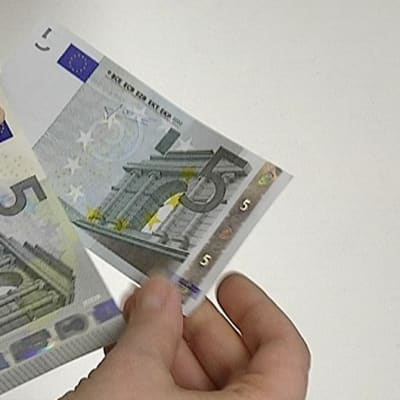 Henkilö pitelee uutta ja vanhaa viiden euron seteliä.