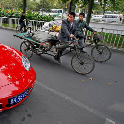 Kaksi polkupyöräilijää katsoo punaista urheiluautoa.
