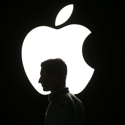 Miehen pään silhuetti Apple-yhtiön logoa vasten.