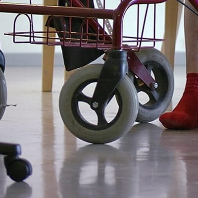 Henkilön jalat rollaattorin vierellä.
