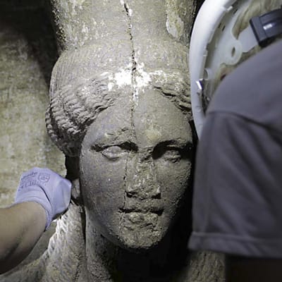 Arkeologit puhdistavat varovasti irtomaasta Pohjois-Kreikasta löytyneen muinaisen haudan naishahmoja.