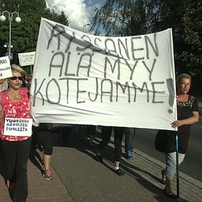 Naiset vievät kylttiä mielenosoituskulkueessa.