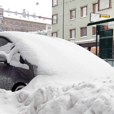 Lumeen peittynyt auto.