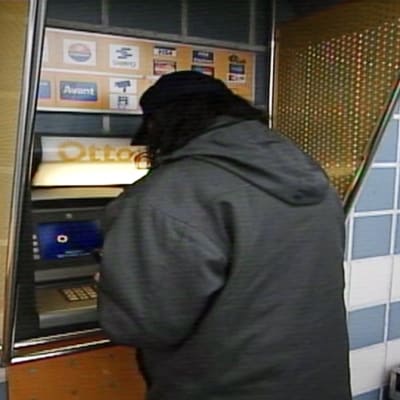 Mies nostaa rahaa pankkiautomaatilta.