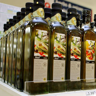 Oliiviöljypulloja rivissä kaupan hyllyllä.