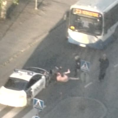 Poliisi ottamassa kiinni alastonta miestä.