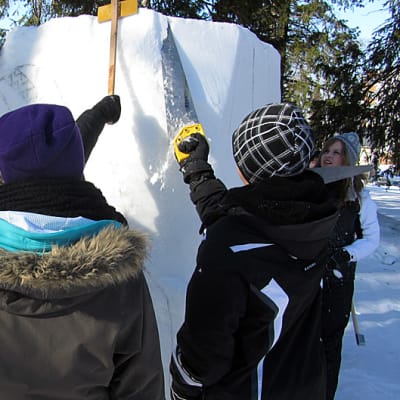 Koululaisia ja maahanmuuttajia tekemässä yhteistä lumiveistosta