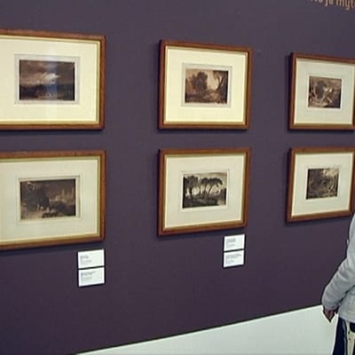 Nainen katselee William Turnerin grafiikkatauluja Tampereen taidemuseossa.