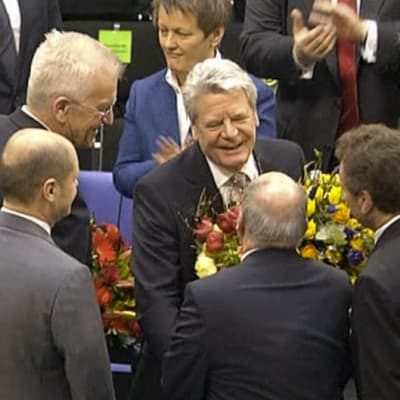 Ihmiset jonottavat onnittelemaan kukkia kädessä pitävää Joachim Gauckia.