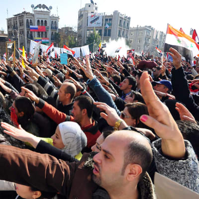 Presidentti Bashar al-Assadin puolesta aukiolle kokoontuneet mielenosoittajat ovat nostaneet oikean kätensä viistosti ilmaan.