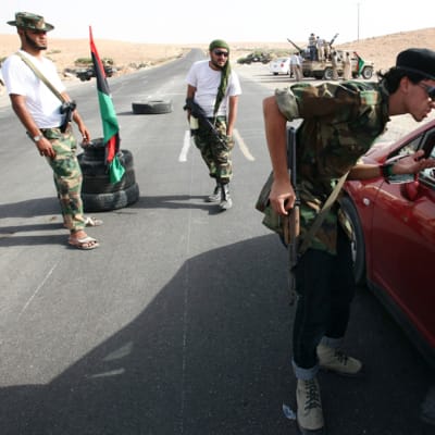 Libyan kapinallissotilaat tarkastavat autoja Tarhunan ja Bani Walidin välisellä maantiellä.