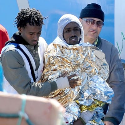 Kaatuneelta pakolaisia kuljettaneelta laivalta pelastunutta miestä talutetaan ensiapuun.