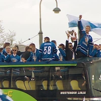 Maailmanmestarijoukkue saapuu Helsingin Kauppatorille kaksikerroksisella bussilla.