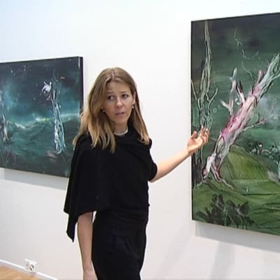 Anna Tuori kertoo maalaustekniikastaan taulun edessä.