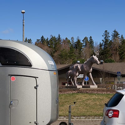 Ypäjän keskustan hevospatsas, etualalla farmariauton vetämä hevoskuljetusvaunu