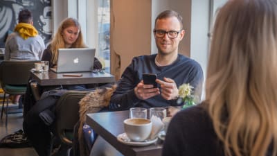 Thomas Kinnaird käyttää älypuhelinta kahvila Bergga:ssa.