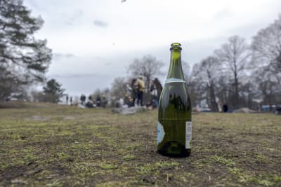 En flaska skumvin i Brunnsparken den 1 maj 2023. I bakgrunden grupper av människor.