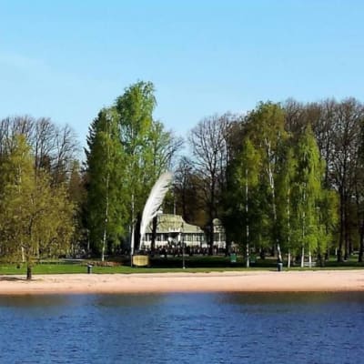 Uimaranta Kokemäenjoen rannassa. Uimarannan taustalla puistoa ja suuri sulkakynäveistos.