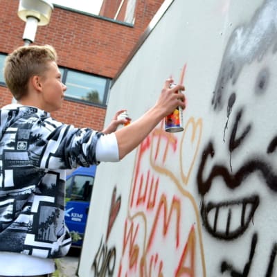 Nuoret pojat maalaamassa graffiteja
