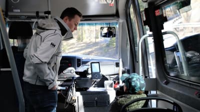 En ung man och ett skolbarn åker buss.