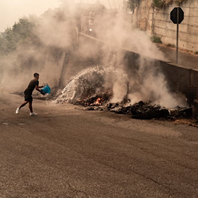 Mies yrittää sammuttaa tulipaloa Mosorrofan kaupungissa Italian Calabriassa 25. heinäkuuta.