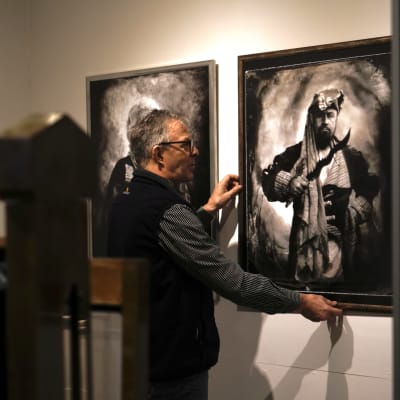 Pekka Homanen asettelee kehystettyjä kuvia esille Kainuun museolla.