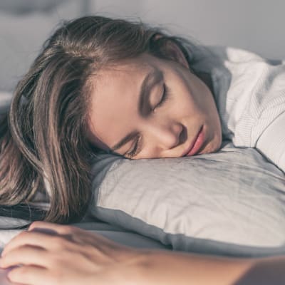 Uttmattad kvinna ligger i en säng