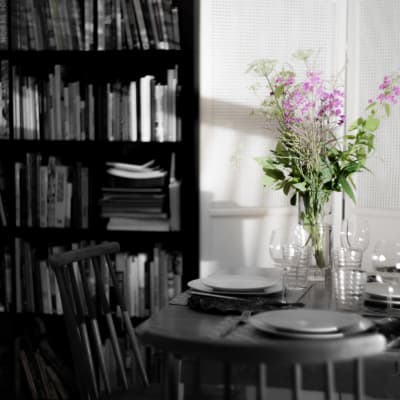 En bukett blommor på ett bord med en enkel festdukning. Endast blommorna har färg i bilden, allt annat är svartvitt.