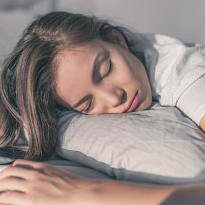 Uttmattad kvinna ligger i en säng