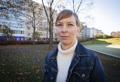 Jenni Pääkkönen fotograferad i en park med gräsmatta täckt av höstlöv. 