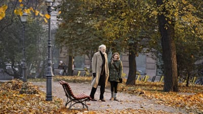 Olavi (Heikki Nousiainen) och Lea (Pirjo Lonka) promenerar tillsammans i en höstlig park.