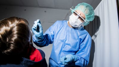En skötare tar ett coronaprov av en 10-årig pojke. 
