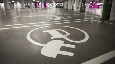 En parkeringsruta för en parkeringsbil. På asfaleten finns en ditmålad vit elsladd.