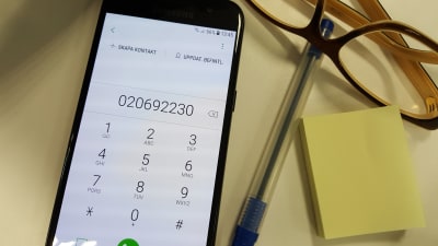 Mobiltelefon ligger på bordet med FPAs servicenummer på skärmen