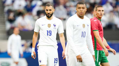 Karim Benzema och Kylian Mbappé går på en fotbollsplan.