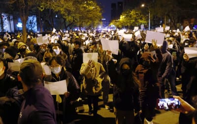 På bilden ses demonstranter hålla vita blanka papper under en protest i Peking mot Kinas covidpolicy.