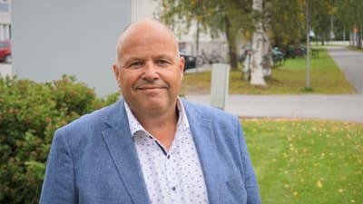 Man i blå kavaj står på en skolgård.