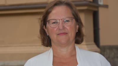 Kvinna framför gul byggnadsfasad.