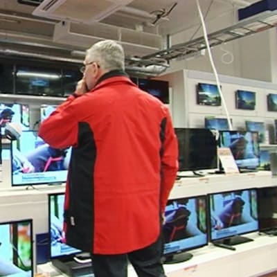 Myyjä ja asiakas katselevat televisioita elektroniikkakaupassa.