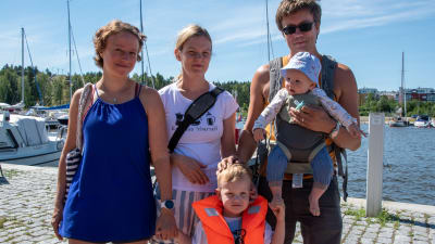 Två kvinnor, en man och två små barn står invid Borgå å. Mannen har bebisen i famnen och den äldre pojken håller en av kvinnorna i handen.
