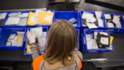 Postanställd sorterar paket