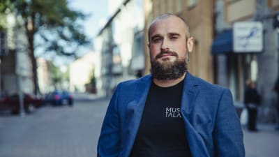 Martin Enroth ser in i kameran, i bakgrunden ett oskarpt stadslandskap.
