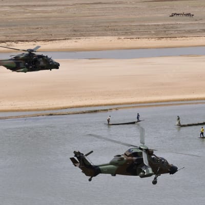kaksi helikopterian lentää joen yllä
